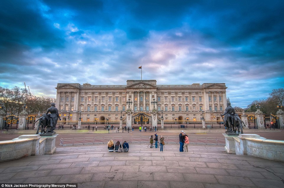 Неторопливое движение: группа туристов изображена перед Букингемским дворцом с беспокойным небом над ним.